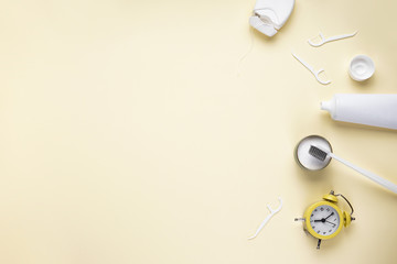 Flat lay composition of yellow alarm clock, toothbrush and toothpaste on a yellow background with space for text. Morning concept.