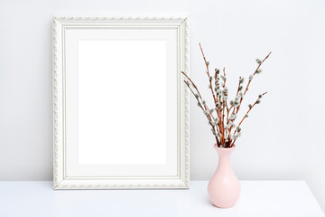 Pink vase with willow and white frame with copy space on a white table