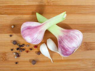 Close up of garlic bulbs and peppercorns on wooden cutting board