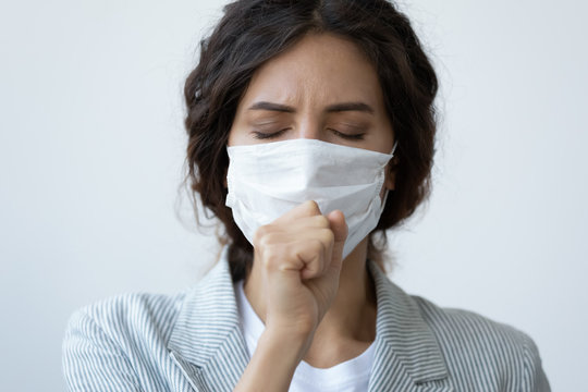 Head shot close up young unhealthy woman in facial medical facemask coughing, responsible for not spreading virus infection, isolated on blue studio background, flu grippe coronavirus quarantine.