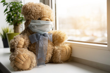 Coronavirus covid-19 and pollution protection concept. teddy bear doll wearing mask, sits on windowsill.