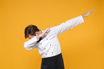 Young bearded male chef cook or baker man in white uniform shirt posing isolated on yellow orange...