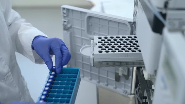genetics worker putting test tubes bottles with DNA into the PCR thermal cycler Spbas or amplifier for diagnostics. concept pharmaceutical, analysis, scientific. pharma machinery