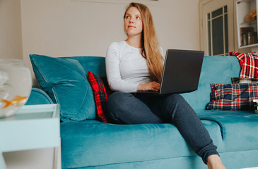 Caucasian girl sitting on the sofa in front of her laptop. Covid concept. Self-defense concept. 