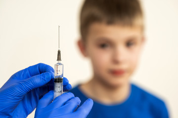 Doctor preparing vaccination injection with a syringe to an afraid child boy. Vaccination of...