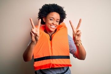 Young African American afro woman with curly hair wearing orange protection lifejacket smiling...