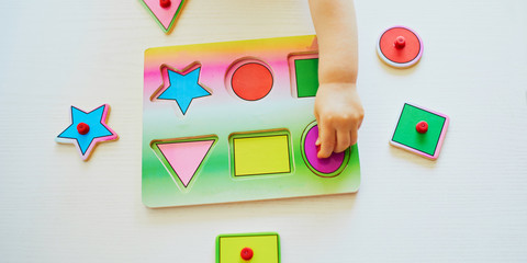 Adorable toddler girl doing wooden puzzle