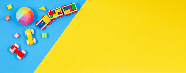 Baby kids toys background. Wooden train, toy car, colorful blocks on blue and yellow background