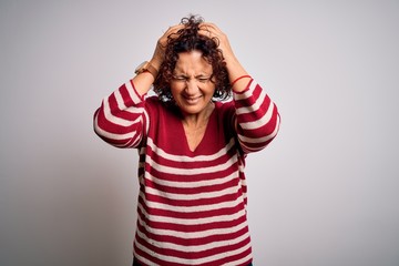 Middle age beautiful curly hair woman wearing casual striped sweater over white background suffering from headache desperate and stressed because pain and migraine. Hands on head.