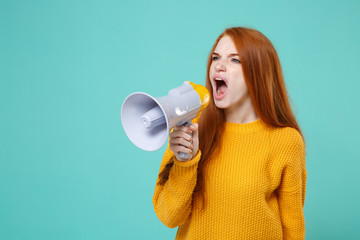 Angry young redhead woman girl in yellow knitted sweater posing isolated on blue turquoise wall...