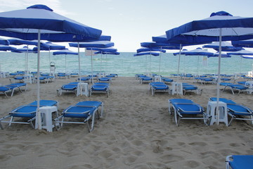 Sun loungers with umbrellas on the beach with sea view.