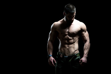 Fototapeta na wymiar Muscular Man Flexing Muscles on Black Background