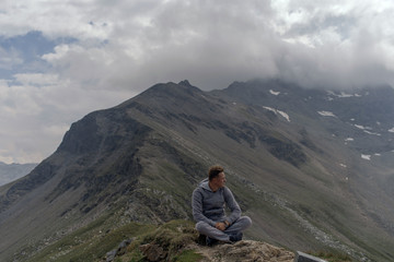 Fototapeta premium Young man meditates on the top of Alpine mountains.