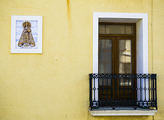 Typical facade with balcony and Virgen de los Desamparados, patron saint of Denia, Alicante, Spain