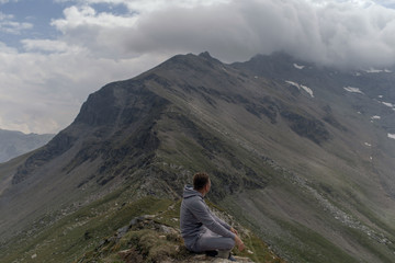 Fototapeta premium Young man meditates on the top of Alpine mountains.