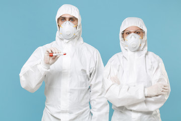 People in protective suit respirator mask hold blood test result Sample tube isolated on blue background studio. Epidemic rapidly spreading coronavirus 2019-ncov originating in Wuhan flu virus concept