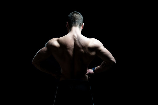 Man Standing and Flexing Muscles on Black Background