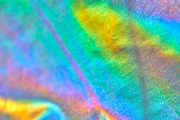 Iridescent holographic fabric background blurred, blue red green yellow violet