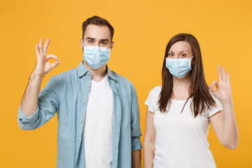 Two people in sterile face masks white t-shirts isolated on yellow background studio. Epidemic...