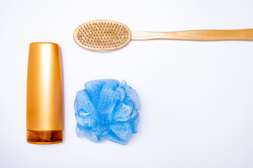 Colorful golden plastic bottle of bodywash, shower gel, blue sponge and a brush for peeling, scrubbing skin on white background, skin and body care concept