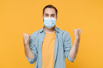 Happy young man in sterile face mask posing isolated on yellow wall background studio portrait....