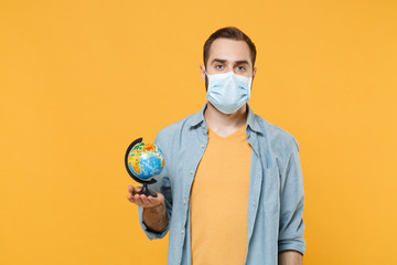 Young man in sterile face mask posing isolated on yellow background studio portrait. Epidemic...