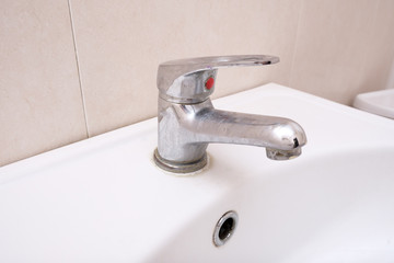 Dirty faucet with limescale, calcified water tap with lime scale on washbowl in bathroom, home cleaning concept