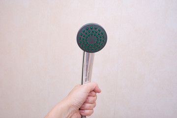 A hand holding shower head in bathroom, cleaning of clogged nozzles