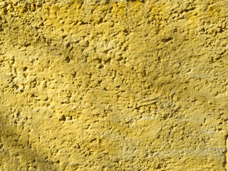 Texture of a yellow rough stucco wall.