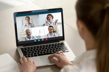 Fototapeta na wymiar View over client shoulder sit at desk receive medical consultation on-line from diverse specialists. Woman listen doctors about corona virus precautionary measures, videoconference laptop webcam view