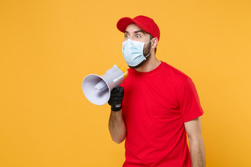 Delivery man in red cap blank t-shirt uniform mask gloves isolated on yellow background studio Guy...