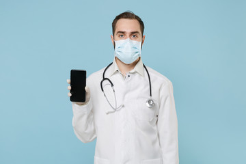 Male online doctor man in medical gown face mask gloves isolated on blue background. Epidemic...
