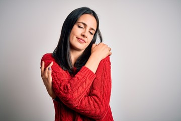 Young brunette woman with blue eyes wearing casual sweater over isolated white background Hugging...