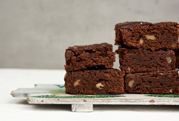 stack of square baked pieces of brownie chocolate cake with walnuts