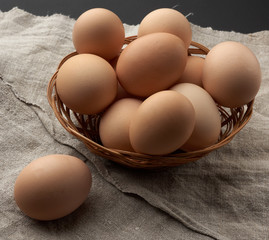 raw brown chicken eggs in a wooden plate on the table