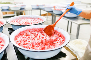 Strawberry jam cooking process. Wooden spoonmixing jam. Organic traditional jam manufacturing.
