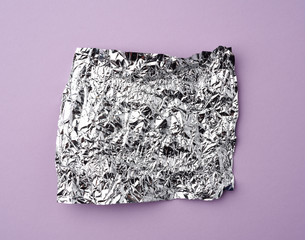 crumpled foil used candy wrappers on a lilac background