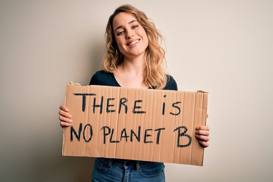 Young blonde activist woman asking for environment holding banner with planet message with a happy face standing and smiling with a confident smile showing teeth