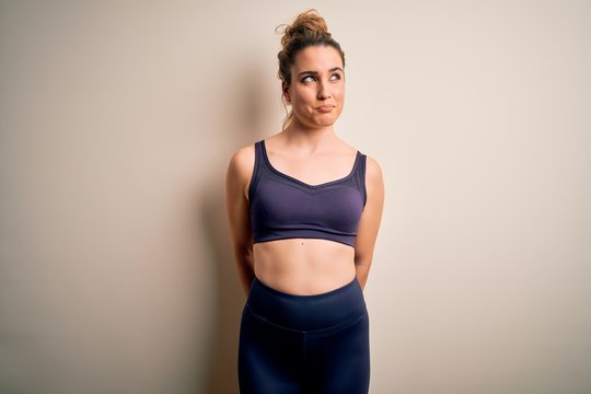 Young beautiful blonde sportswoman doing sport wearing sportswear over white background smiling looking to the side and staring away thinking.