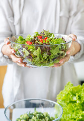 Unrecognizable woman preparing a green mixed salad in the kitchen