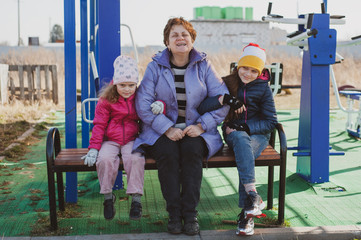 Spring portrait of a happy grandmother and her two granddaughters outside. Girls and woman in outerwear. Family Values Concept