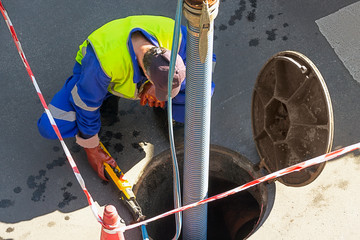 sewerage truck service and utility workers for cleaning sewer pipes in city street - obrazy, fototapety, plakaty