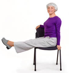 Happy charming beautiful elderly woman doing exercises at home on a chair. Workout gymnastics for health. On a white background