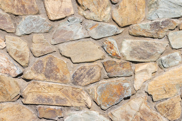 detail of sunlit grey and brown natural stonewall 