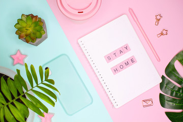 Concept flat lay. Words "STAY HOME" made of wooden letters on notepad and palm leaves