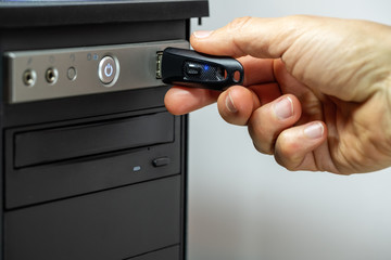 Hand inserting a USB flash drive into a computer.