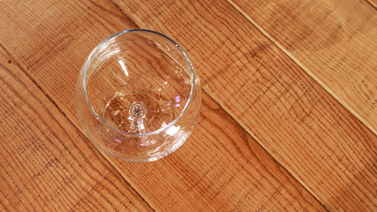 Empty wineglass on the yellow wooden table. Space for text.