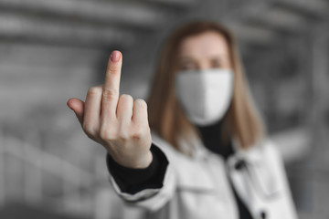 Go away from here. Woman with surgical medical mask showing fuck sign at camera. Coronavirus. Covid...