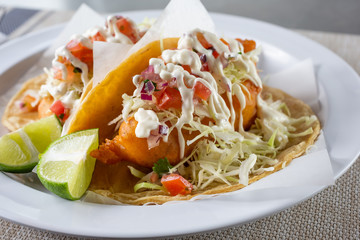 A view of a plate of fish tacos, in a restaurant or kitchen setting.