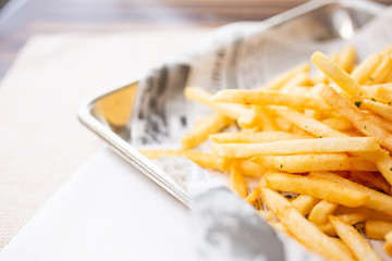 A view of a tray of french fries, cut off on the right side of the frame, in a restaurant or kitchen setting.